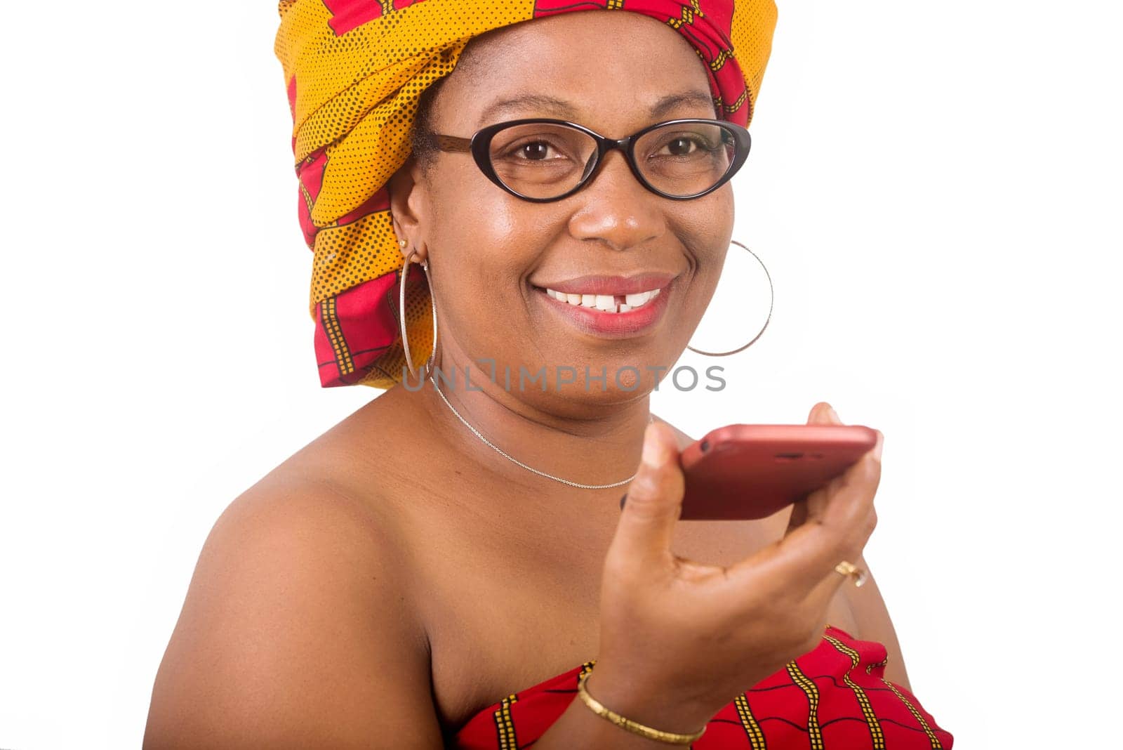 mature woman in traditional dress standing on white background communicating on mobile phone and looking at camera smiling.