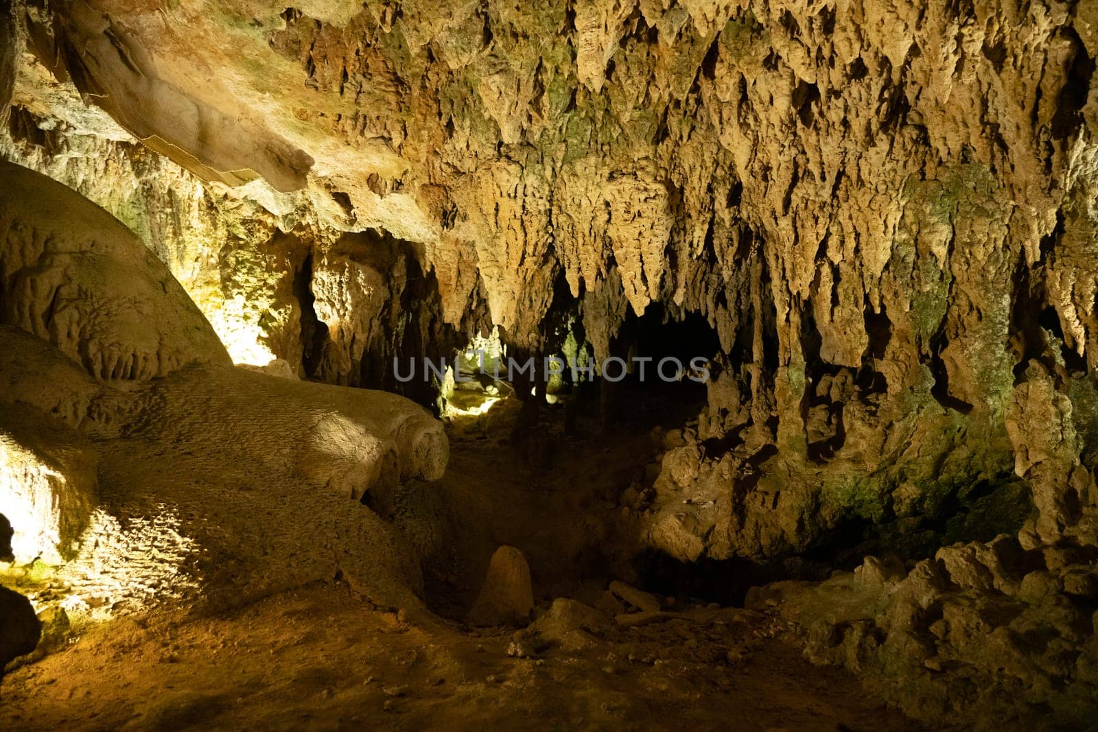 A cavern filled with limestone rocks formed by erosion, with soda straws, stalagmites, and stalactites illuminated by a shining light