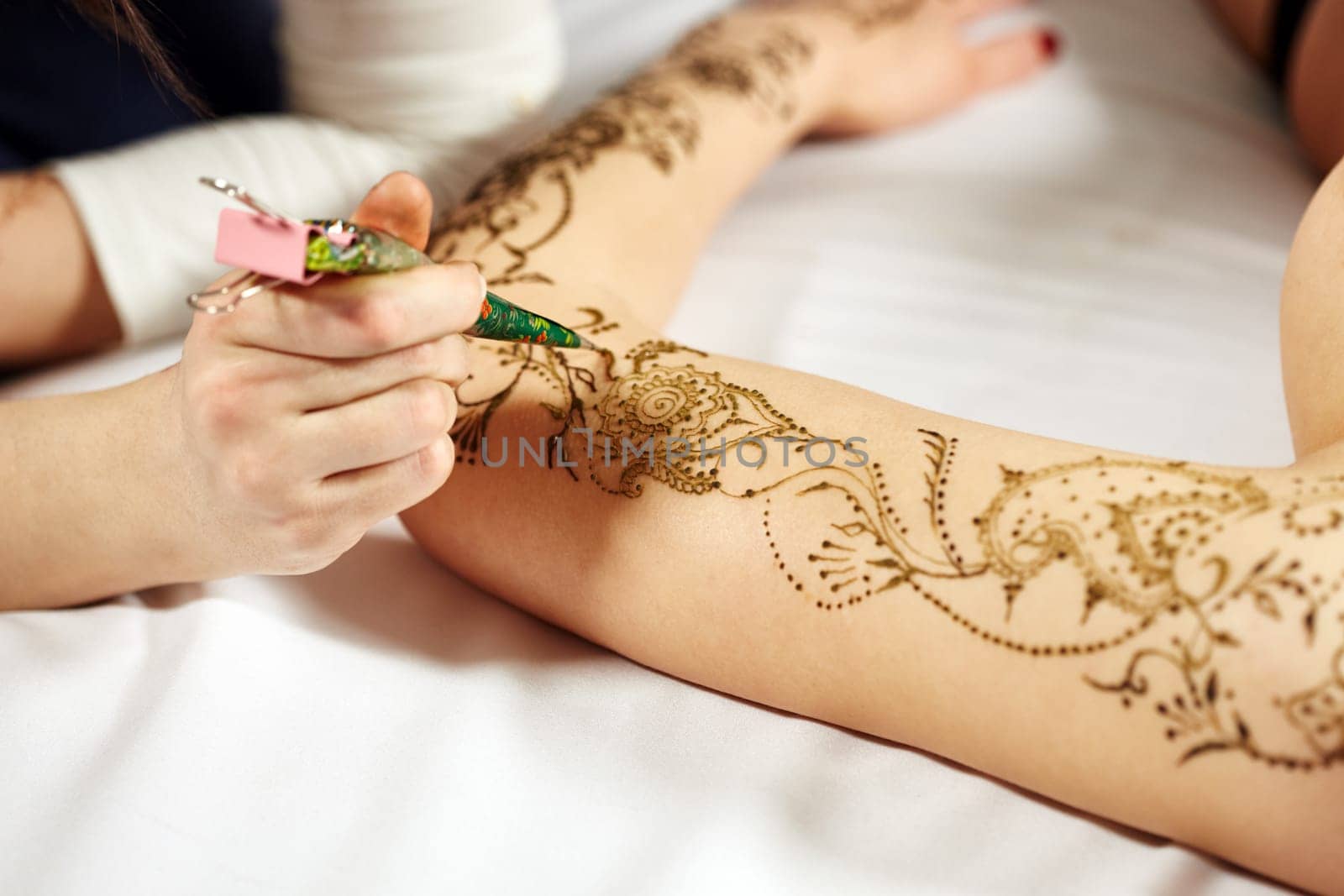 Mehndi. Master applying henna on model's hand, close-up