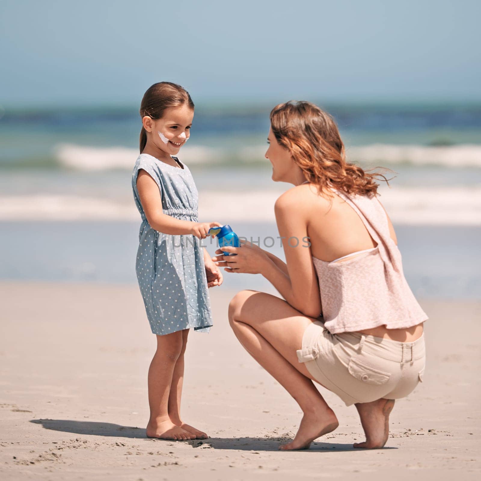 Mother, child and sunscreen with skincare health on beach for summer holiday, tropical island or bonding. Female person, daughter and lotion application at California seaside, protection or safety.
