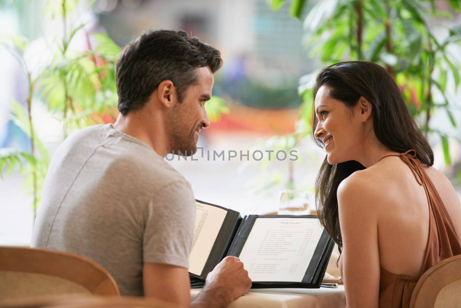 Couple, restaurant and menu for conversation, selection and bonding on valentines day. People, love and romance at cafe or lunch choice for anniversary celebration, cuisine and happy at bistro.