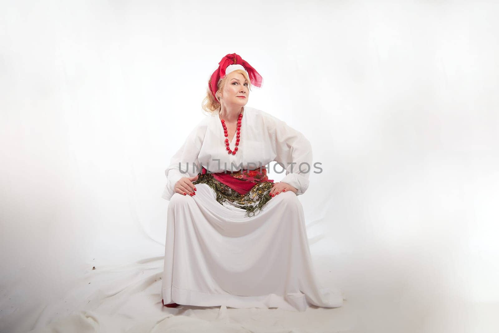 Portrait of cheerful funny adult mature woman solokha. Female model in clothes of national ethnic Slavic style. A stylized Ukrainian, Belarusian or Russian woman poses in a comic photo shoot