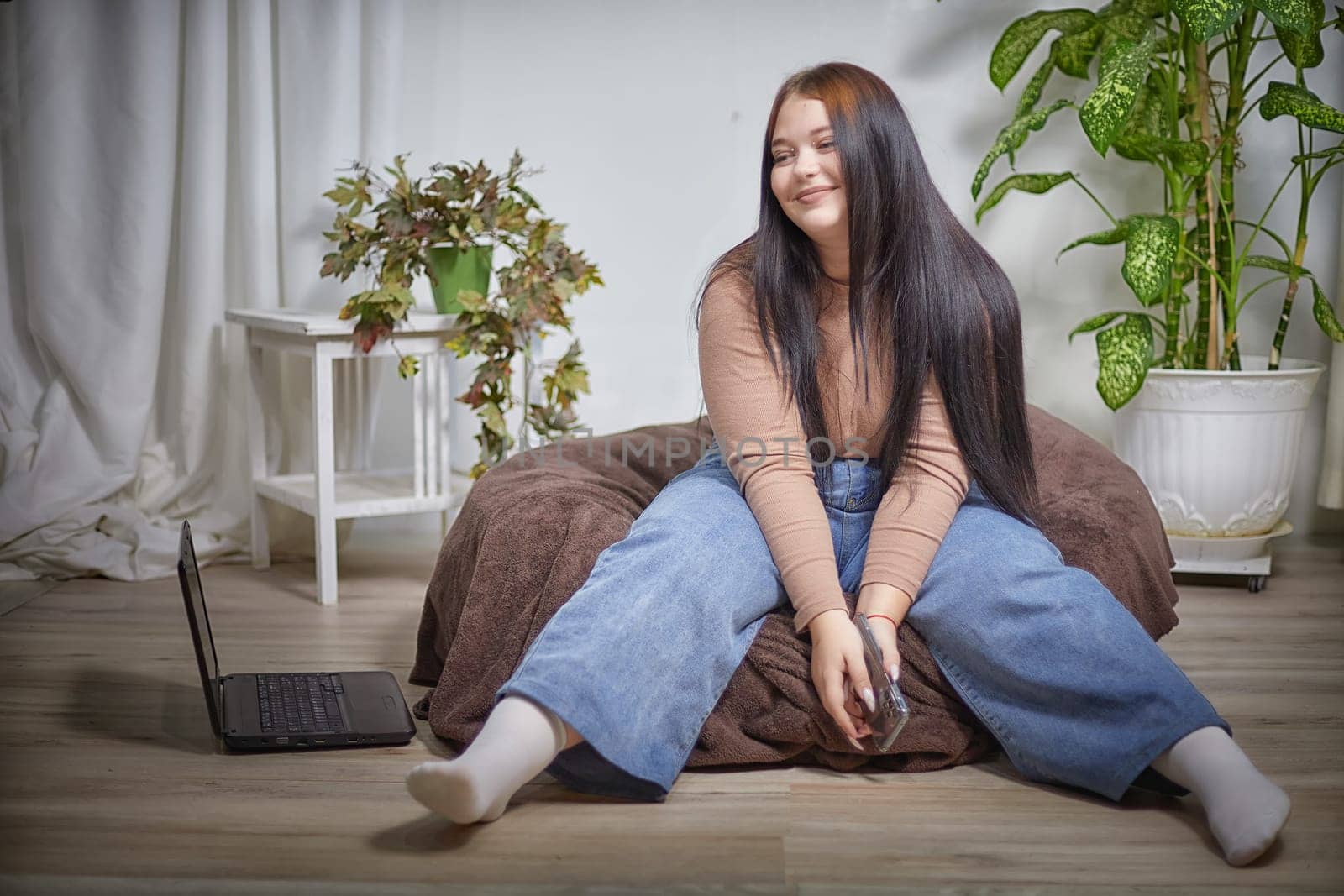 Stylish chubby student brunette girl with cell mobile phone. Attractive young brunette overweight indoors