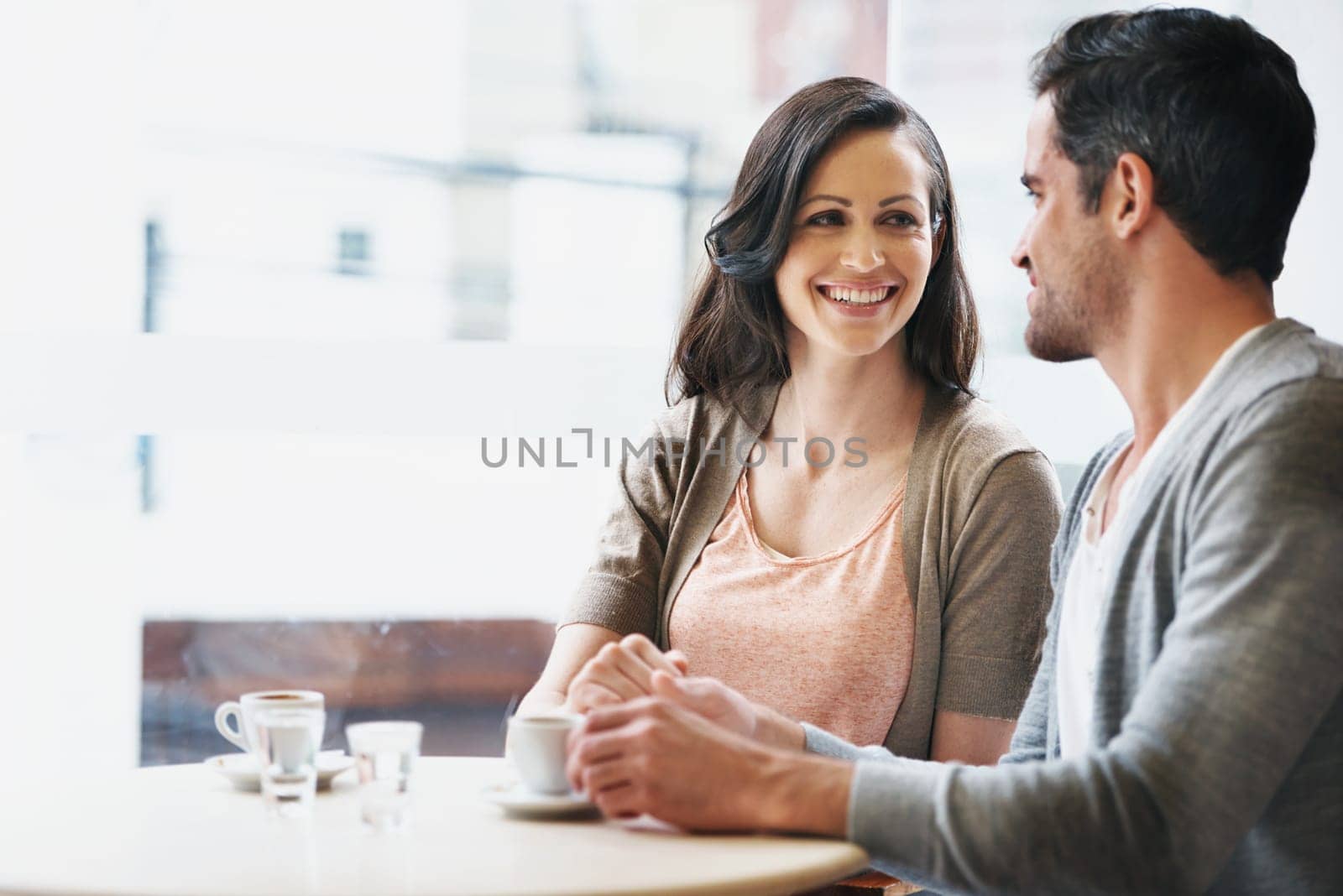 Smile, conversation and couple with coffee on date for romance or anniversary in cafeteria. Happy, love and young man and woman talking and drinking latte, espresso or cappuccino at restaurant