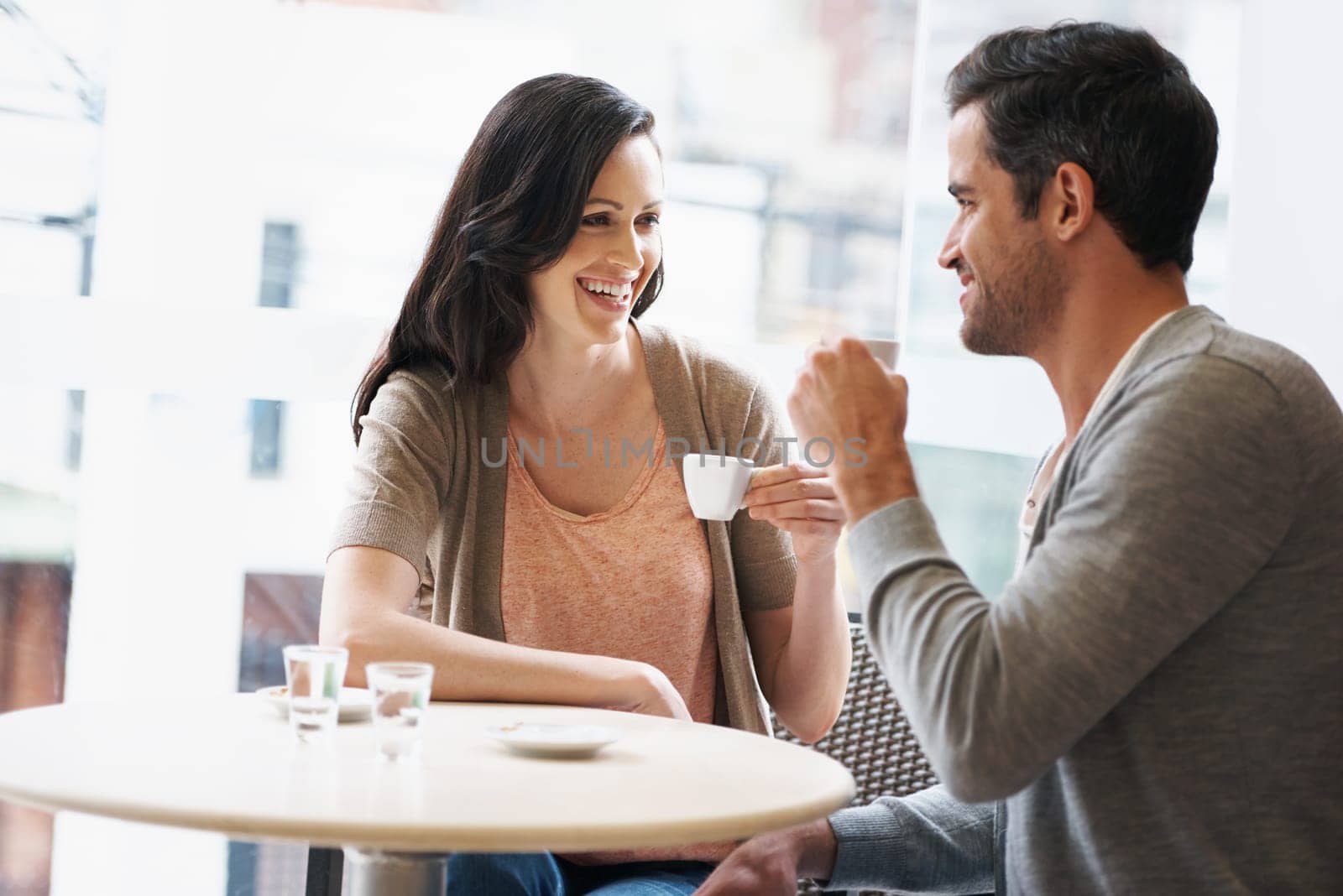 Happy, love and couple with coffee on date for romance or anniversary in cafeteria. Smile, conversation and young man and woman talking and drinking latte, espresso or cappuccino at restaurant