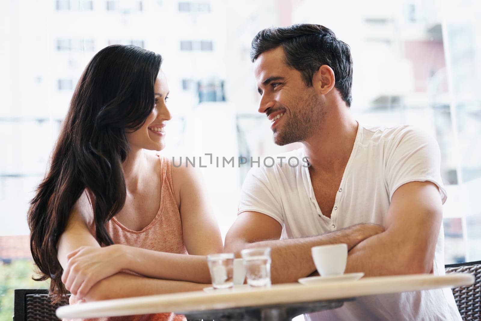 Love, discussion and couple with coffee on date for romance or anniversary in cafeteria. Happy, bonding and young man and woman talking and drinking latte, espresso or cappuccino at restaurant