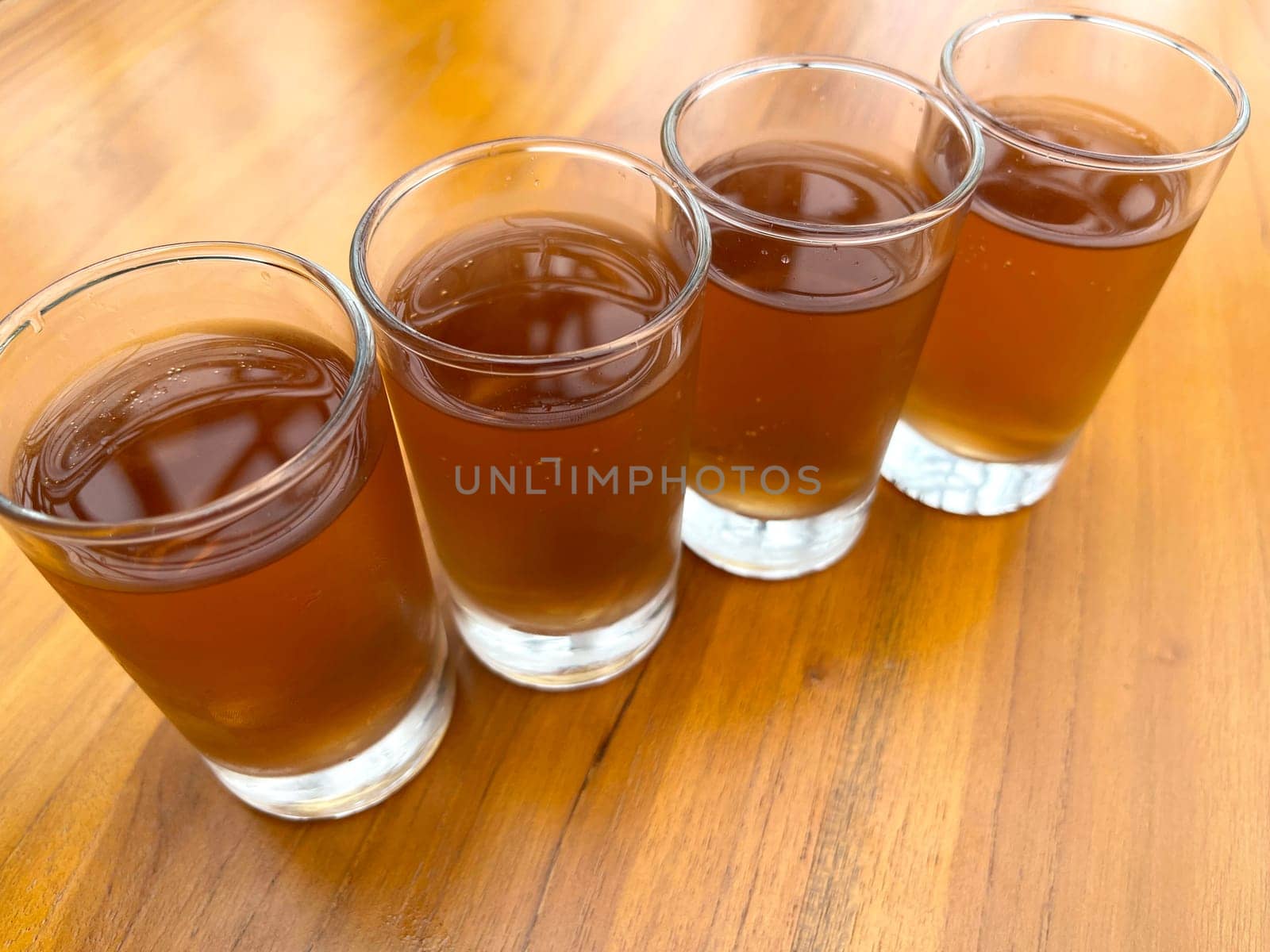 Fresh cold Apple juice in four clear glass with wooden background serves for breakfast
