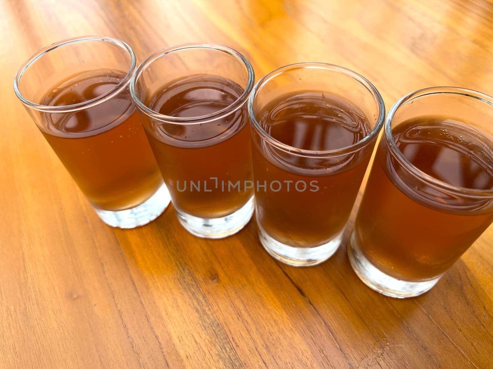 Fresh cold Apple juice in four clear glass with wooden background serves for breakfast