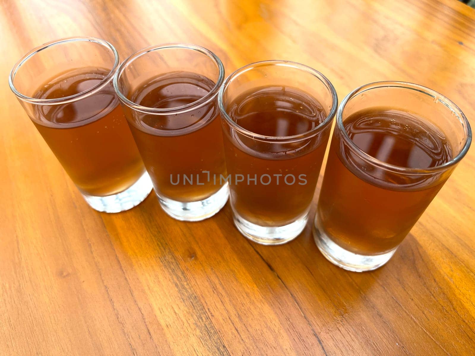 Fresh cold Apple juice in four clear glass with wooden background serves for breakfast