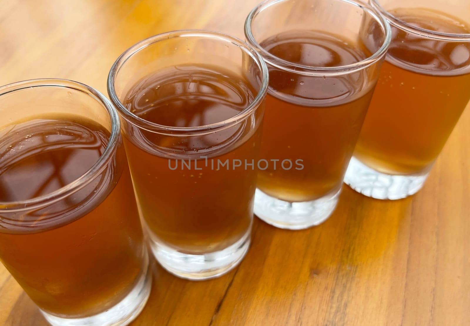 Fresh cold Apple juice in four clear glass with wooden background serves for breakfast