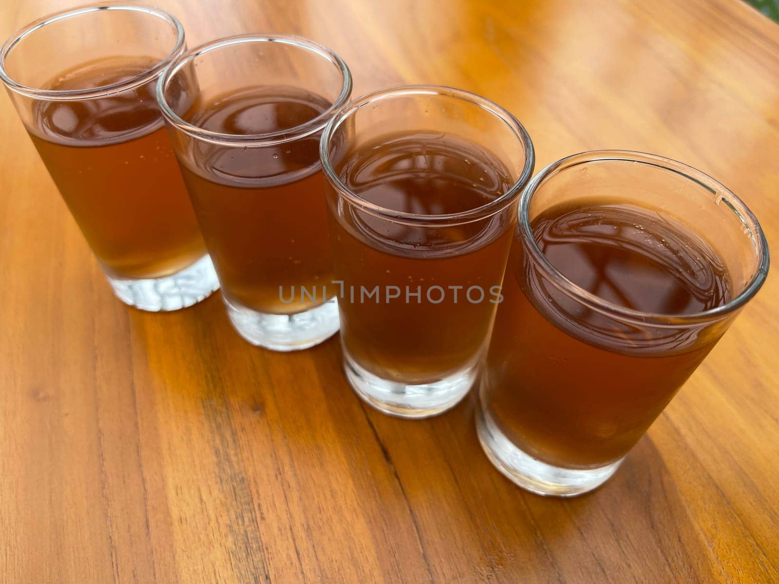 Fresh cold Apple juice in four clear glass with wooden background serves for breakfast