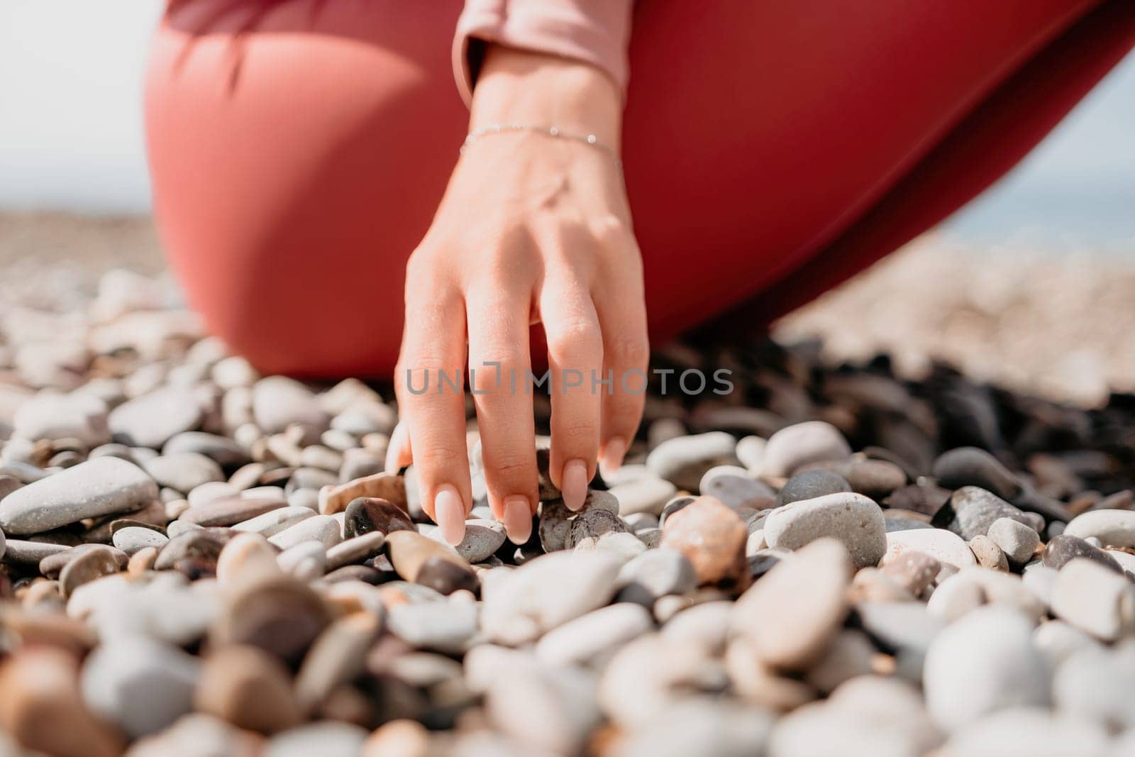 Young woman with long hair in white swimsuit and boho style braclets practicing outdoors on yoga mat by the sea on a sunset. Women's yoga fitness routine. Healthy lifestyle, harmony and meditation