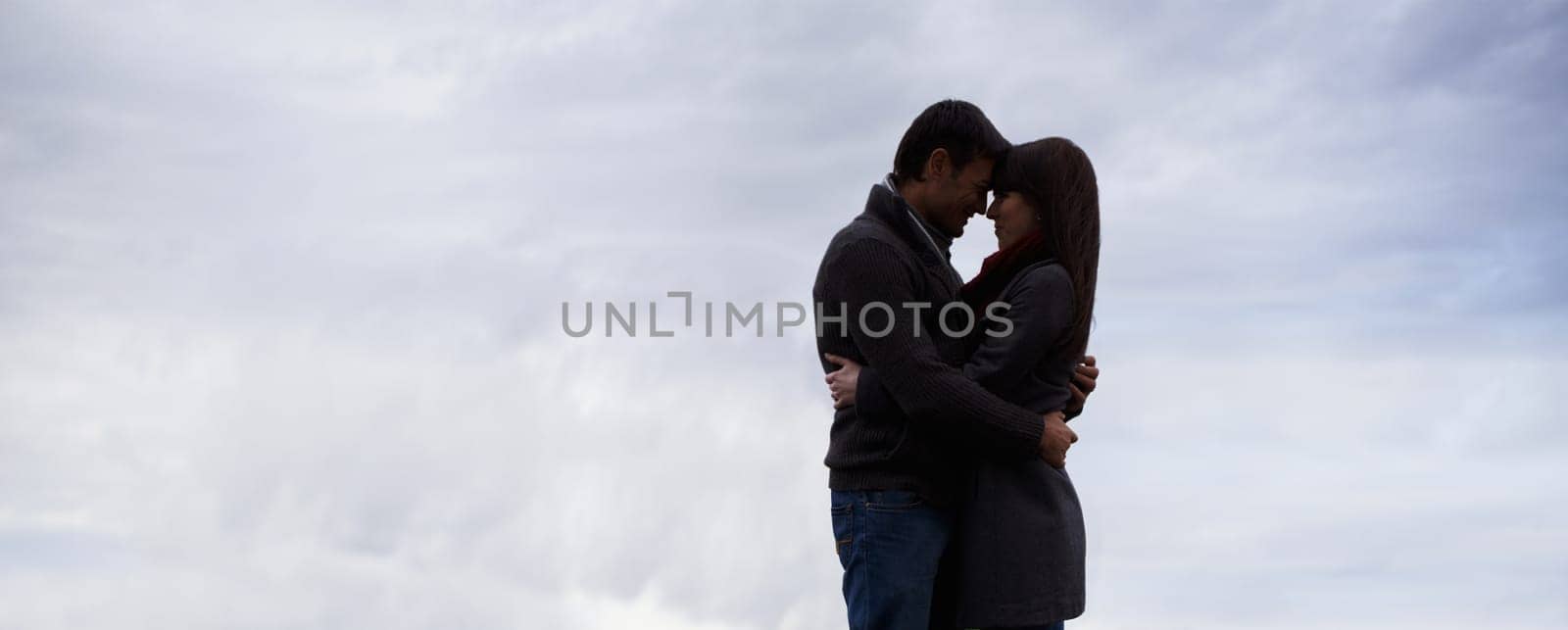 Couple, sky and hug together with love for romance, commitment and care for feeling safe. Man, woman and relationship with mockup, space and banner outdoors on honeymoon with spouse comfort and trust.