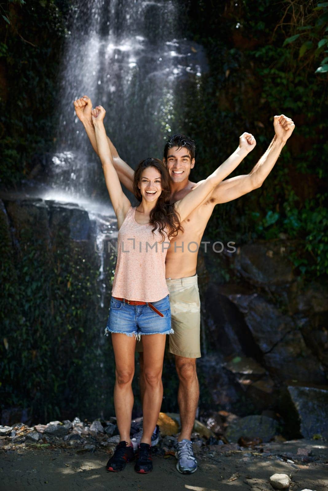 Success, waterfall or portrait of happy couple in nature or journey on outdoor trekking adventure. Excited, victory or proud people cheering on holiday vacation for exercise goals, travel or wellness.
