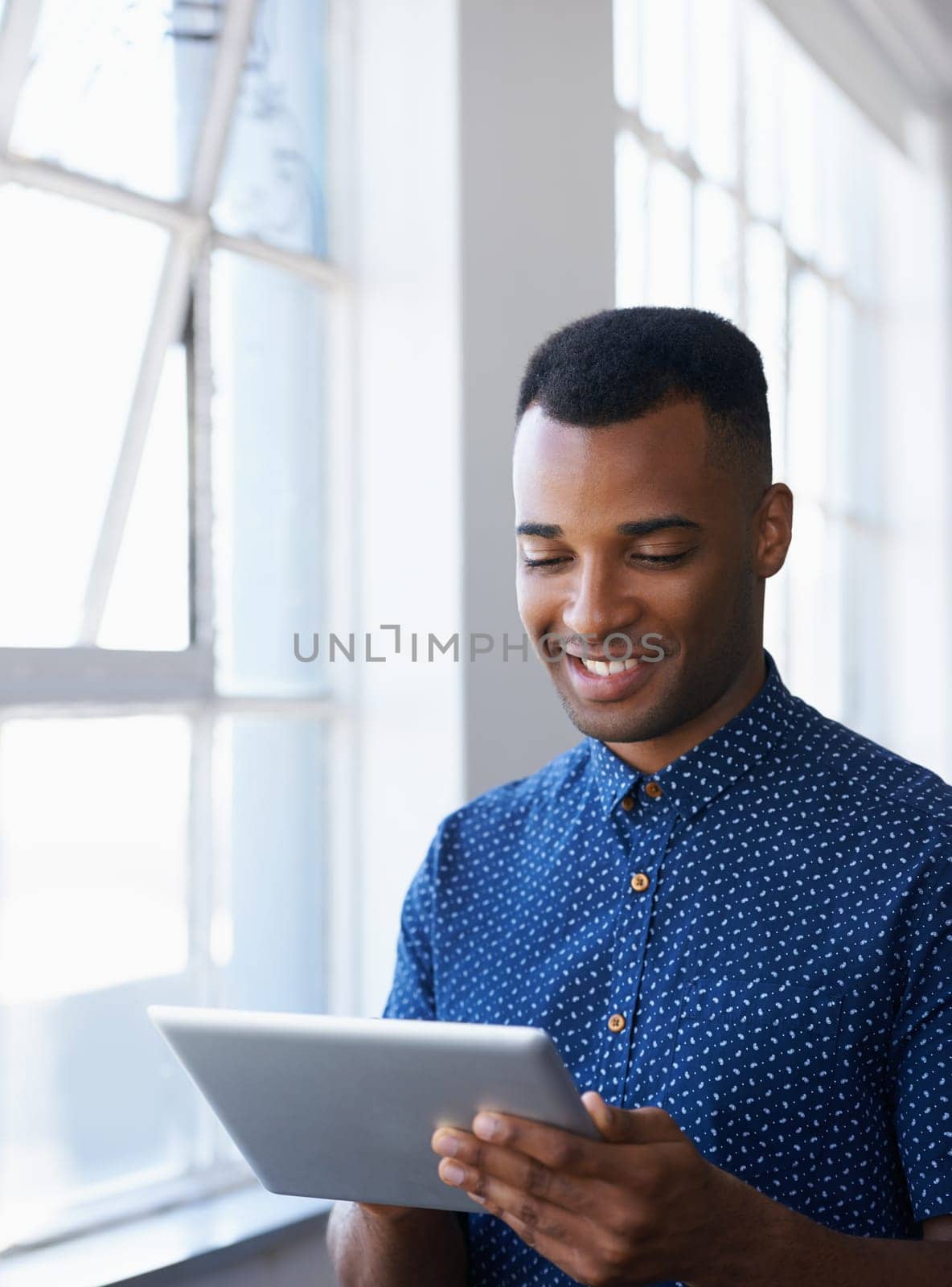 Businessman, tablet and online at window for networking, internet search and communication in office. Entrepreneur, african employee and happy with technology for corporate email and planning at work.