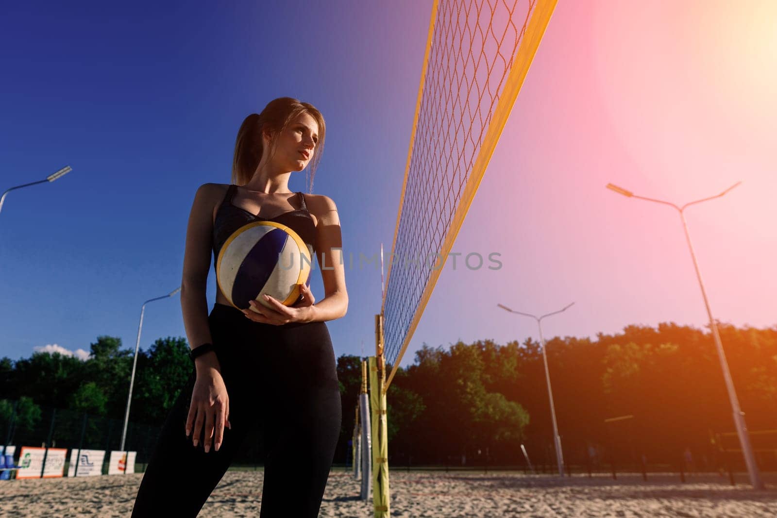 A female beach volleyball athlete with ball on the volleyball court by Zelenin