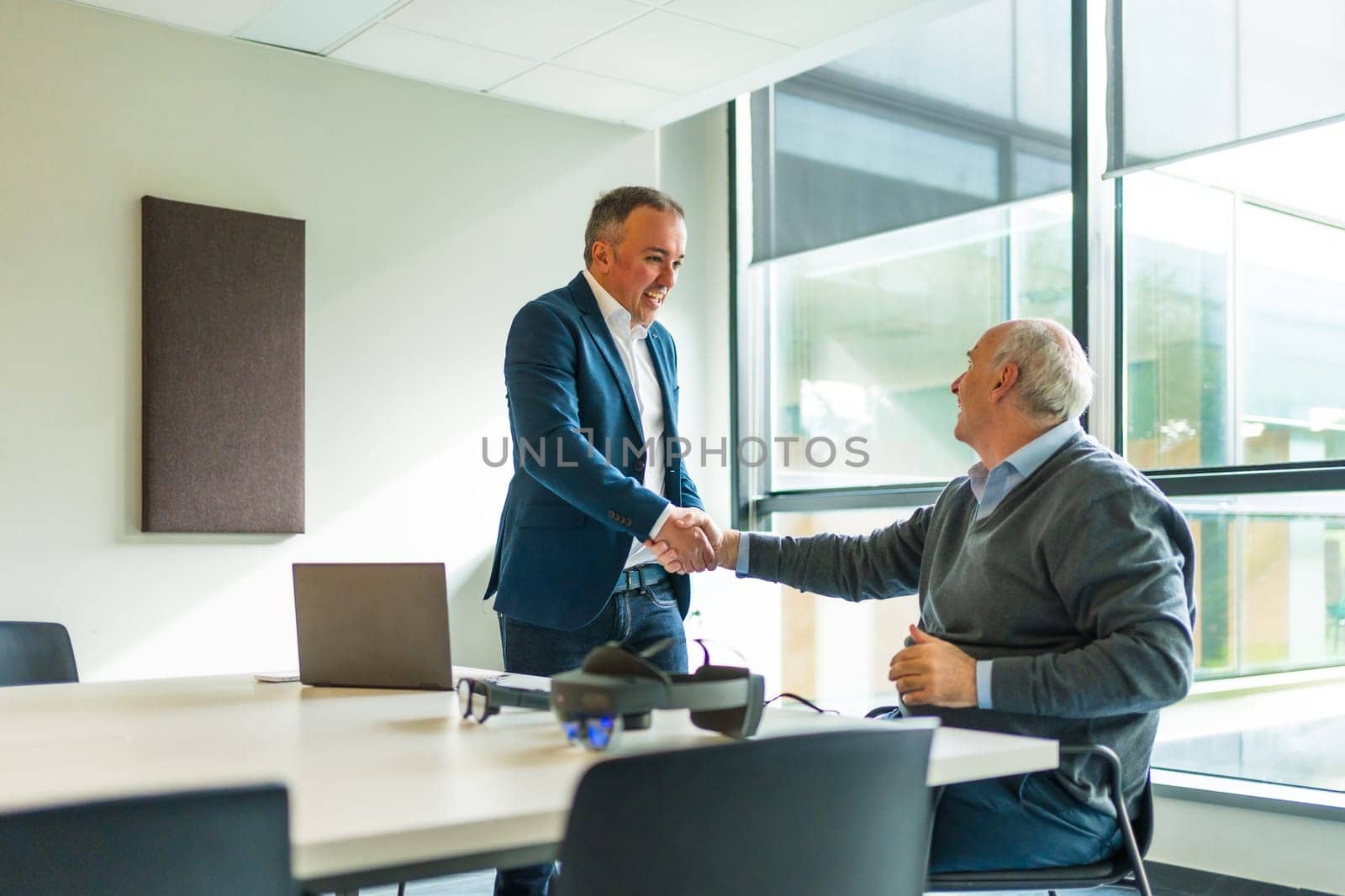 Business people shaking hands next to futuristic goggles by Huizi