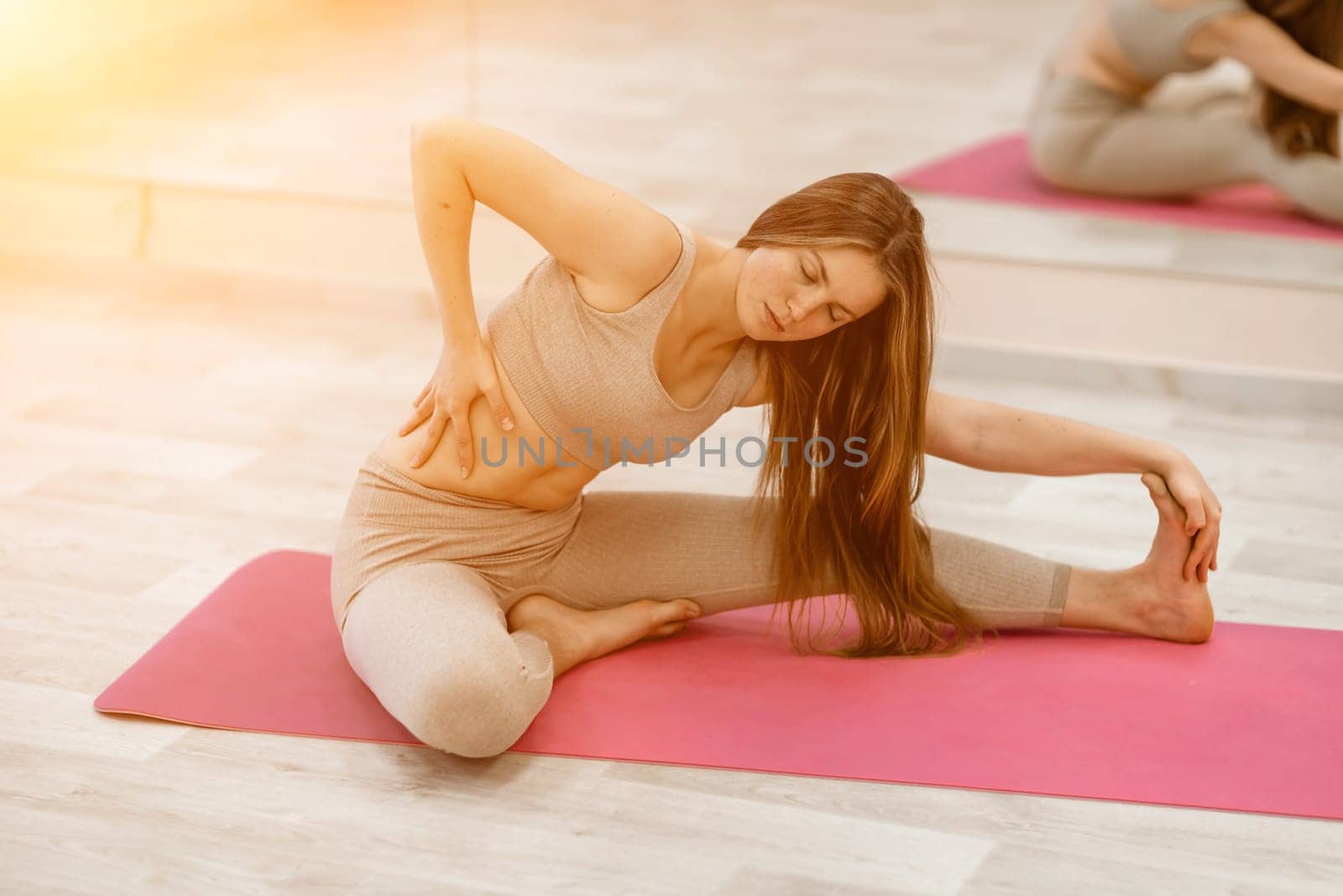 Girl does yoga. Young woman practices asanas on a beige one-ton background