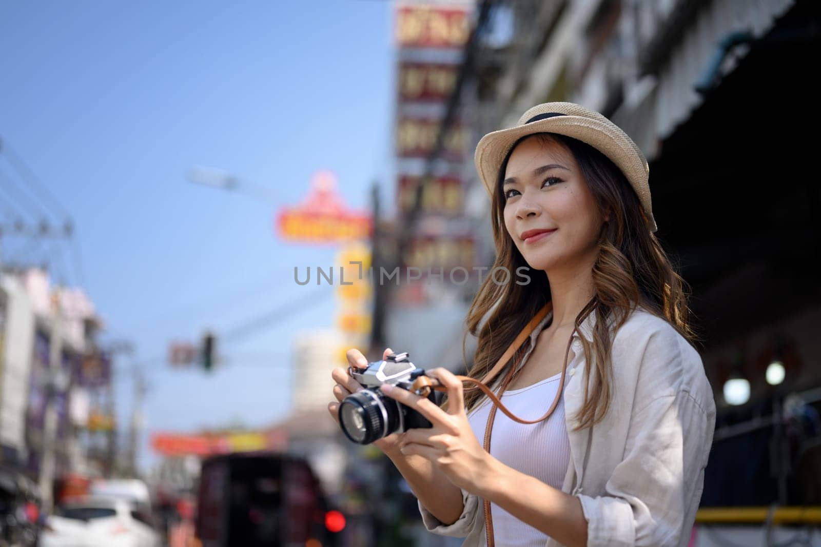 Attractive young female tourist with camera walking on Chinese town street.