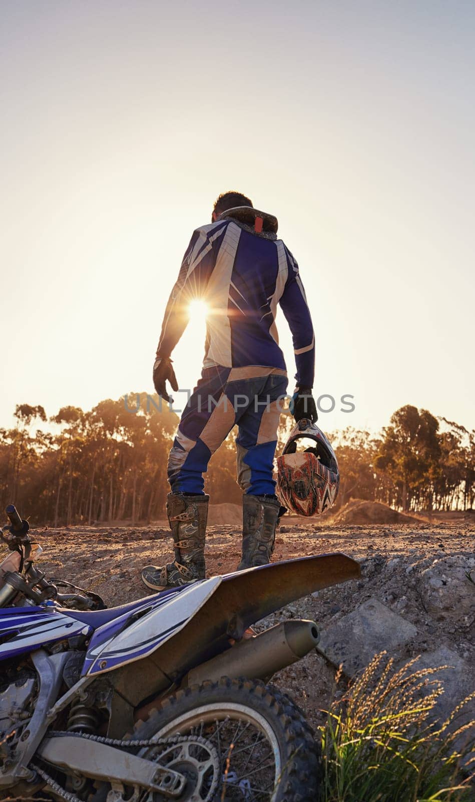 Motorcycle, sports and danger with back view of biker person outdoor, sunlight with uniform for riding on dirt track. Speed, power and risk with motorbike, transportation and adventure for adrenaline by YuriArcurs