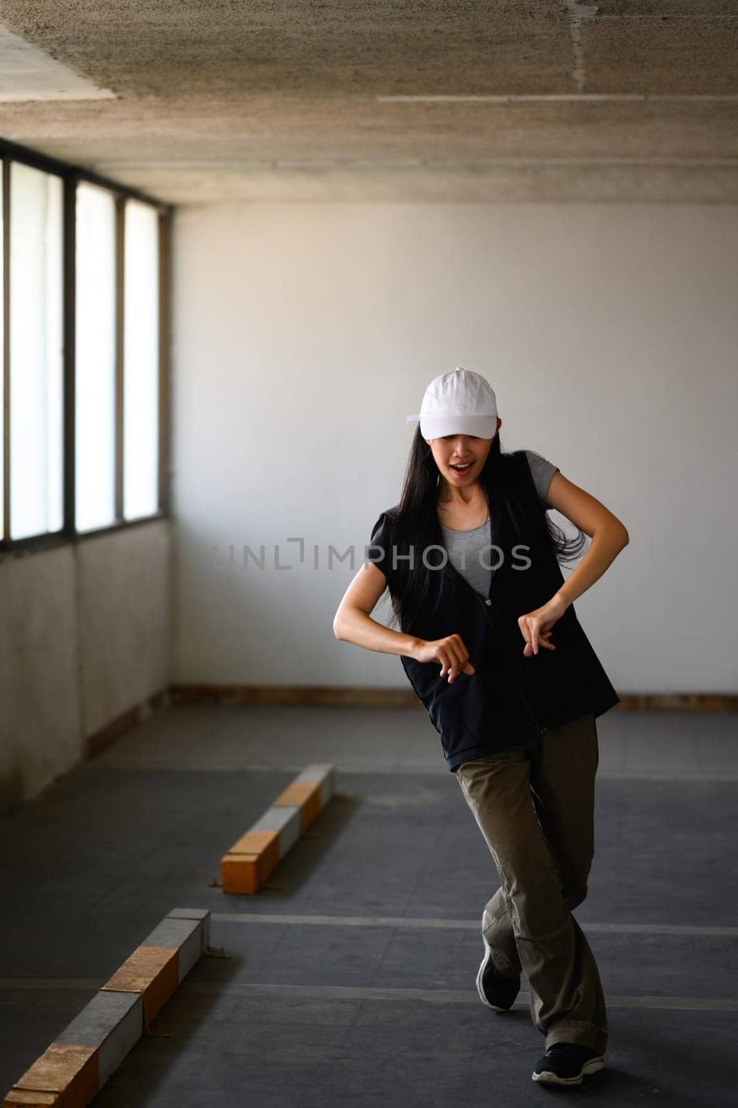 Young beautiful hip hop dancer dancing in parking garage. Movement and active lifestyle concept.