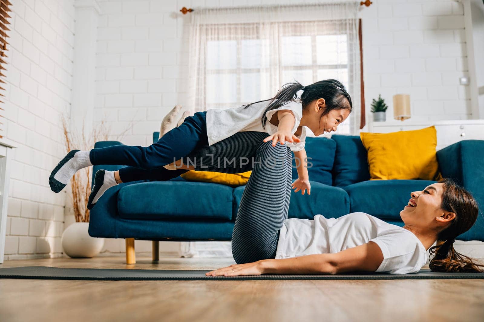 A harmonious family practices the little bird posture in yoga at home by Sorapop