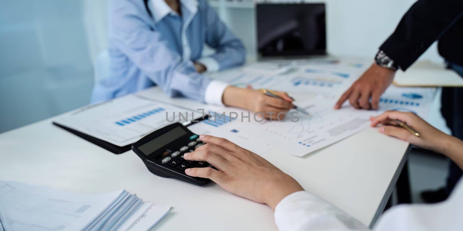 Businesswoman using a calculator to calculate numbers on a company's financial documents, she is analyzing historical financial data to plan how to grow the company. Financial concept by itchaznong