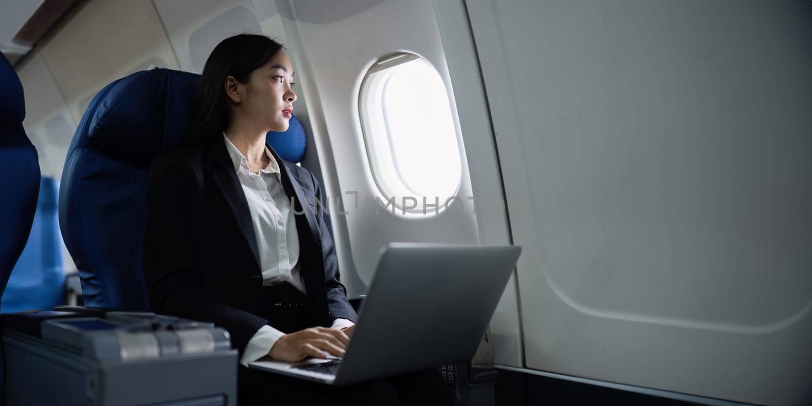 Beautiful Asian businesswoman working with laptop in aeroplane. working, travel, business concept by itchaznong