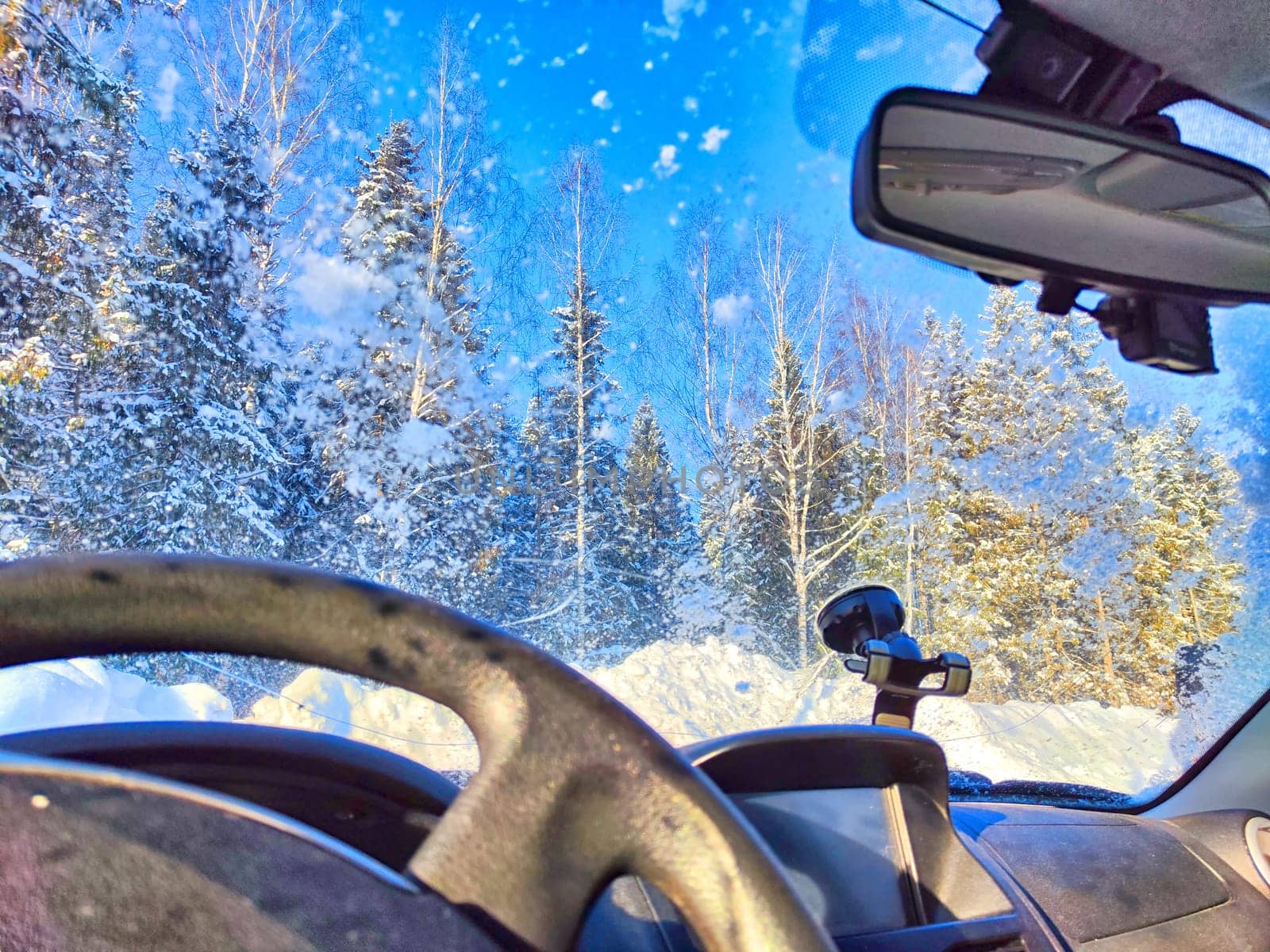 Snow on the windshield and Snowy Road View From Inside a Car During Winter Day. Snowfall on the road in nature forest. Car interior in winter travel