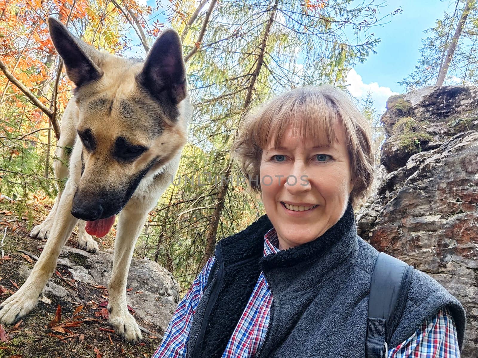 Adult girl with shepherd dog taking selfies in forest. Middle aged woman and big shepherd dog on nature. Friendship, love, communication, fun, hugs