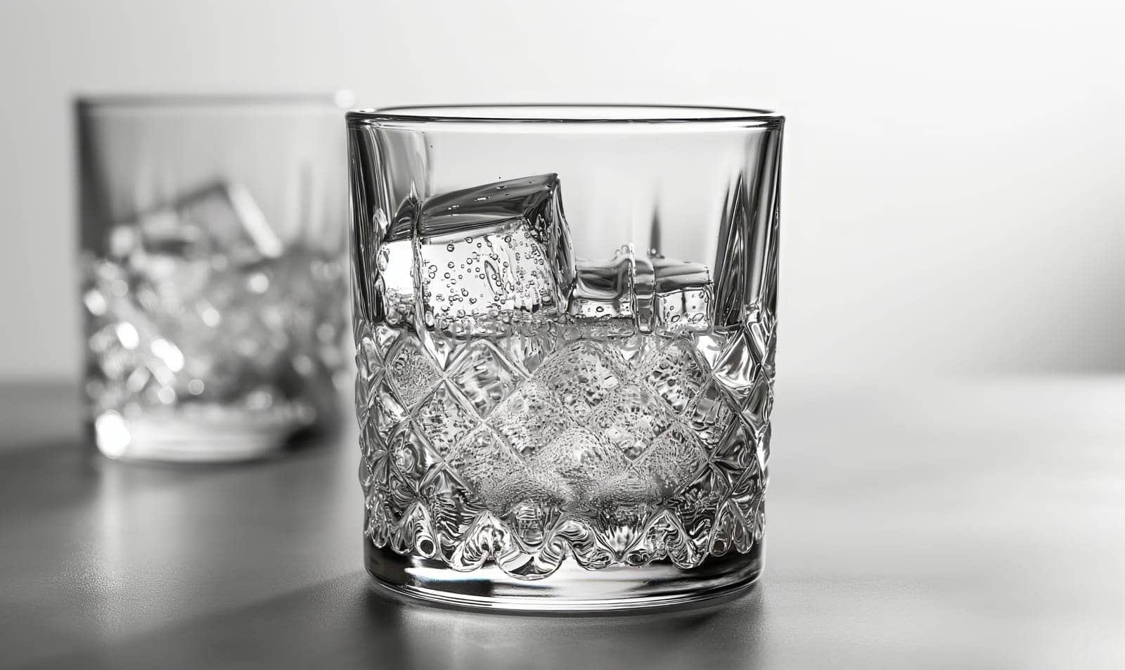 Transparent glass with clear drink and ice cubes. by Fischeron