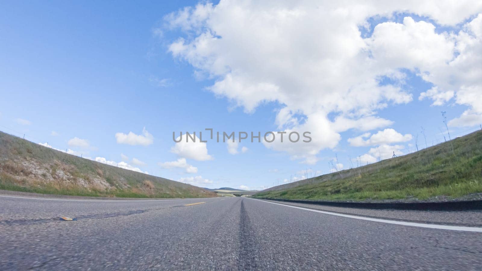 On a clear winter day, a car smoothly travels along Highway 101 near Santa Maria, California, under a brilliant blue sky, surrounded by a blend of greenery and golden hues.