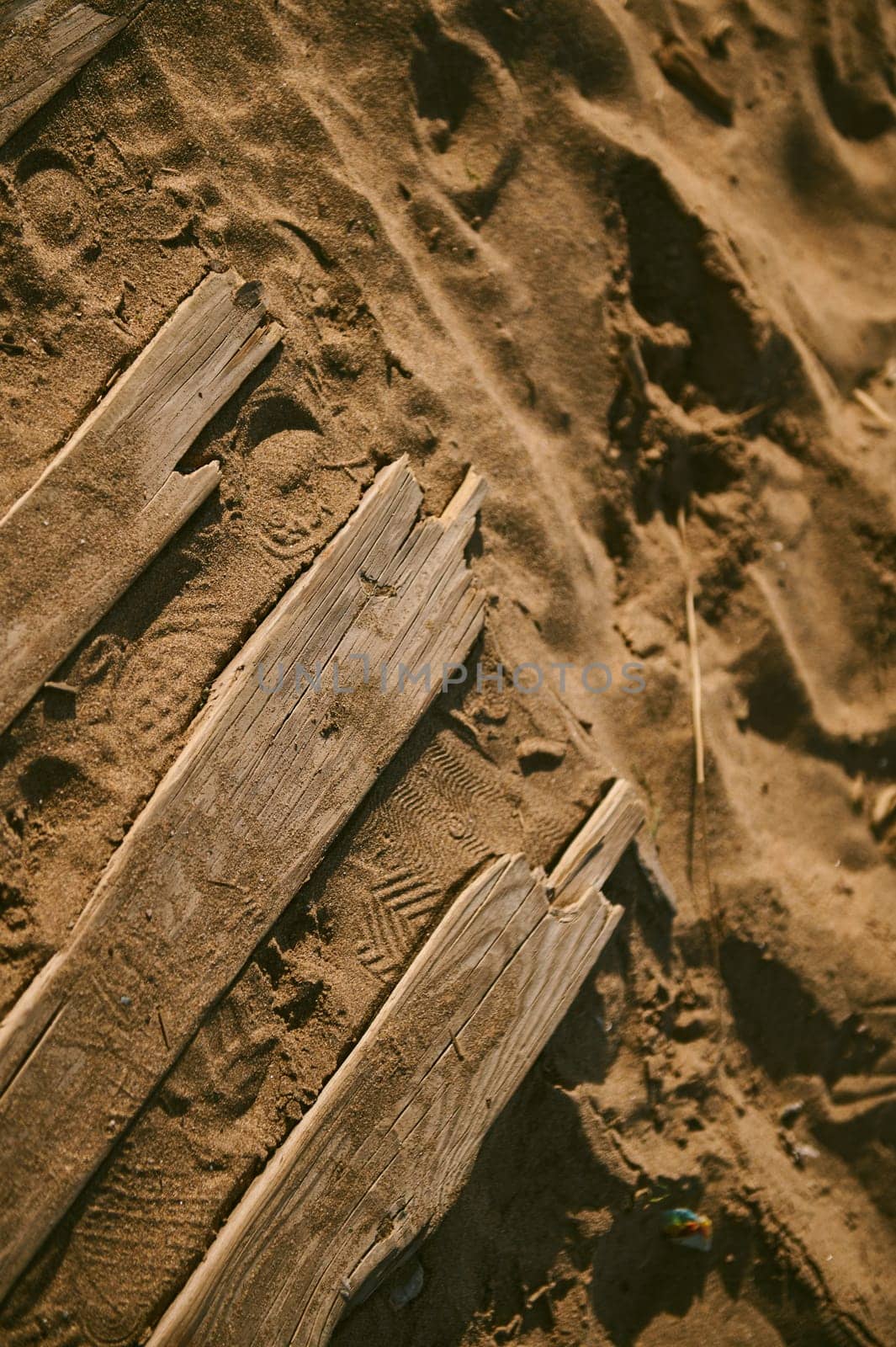 View from above of weathered old damaged wooden boards on the sand.