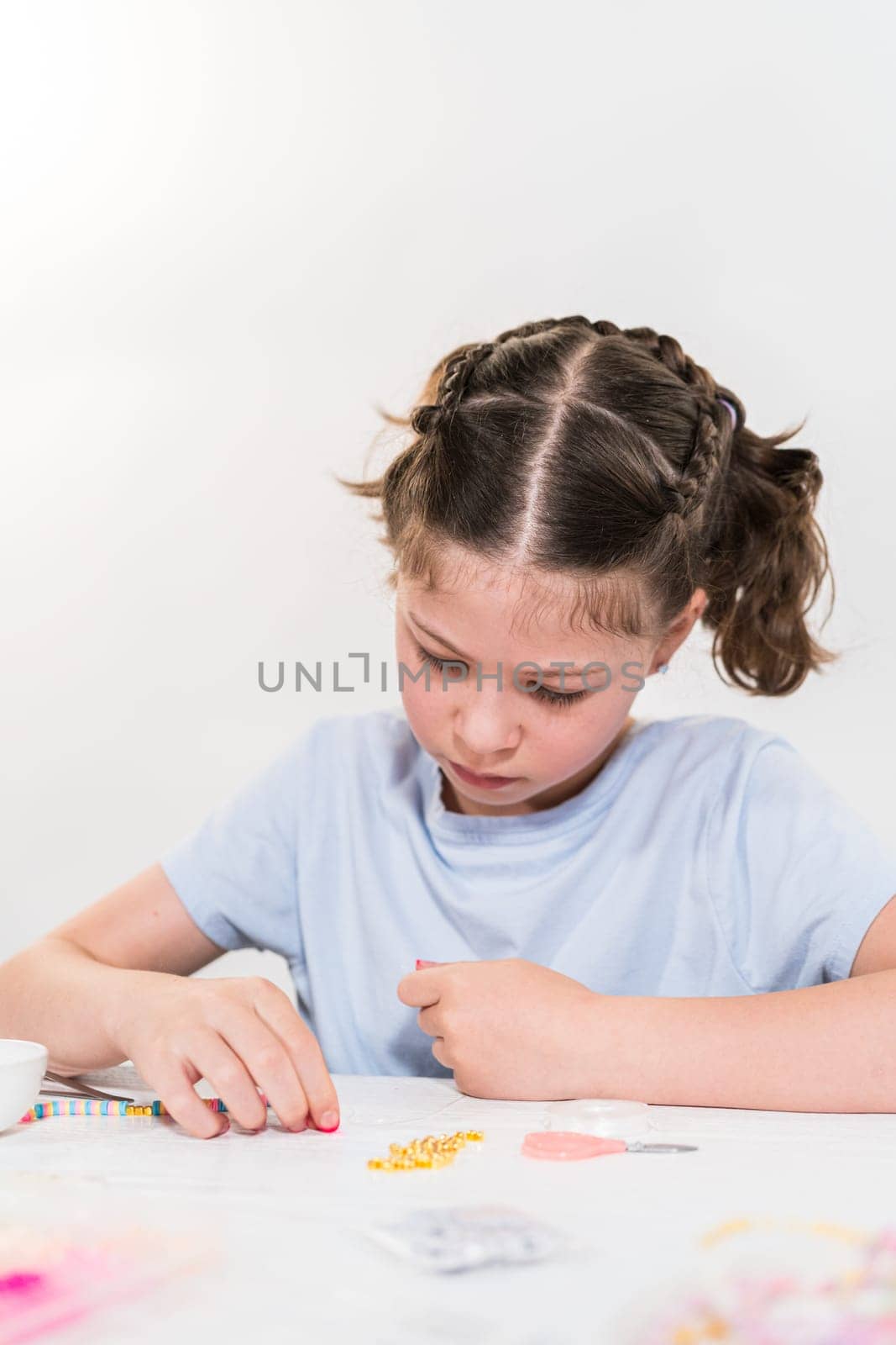 Little girl enjoys crafting colorful bracelets with vibrant clay beads set.