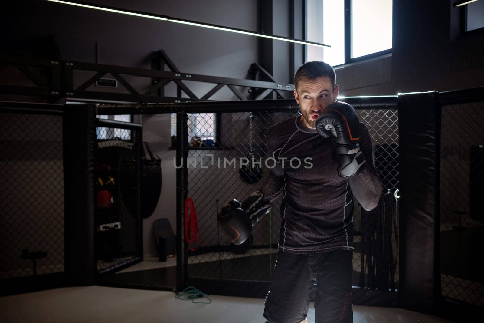 Fighter training punches during shadow fight on octagon in boxing gym by nazarovsergey