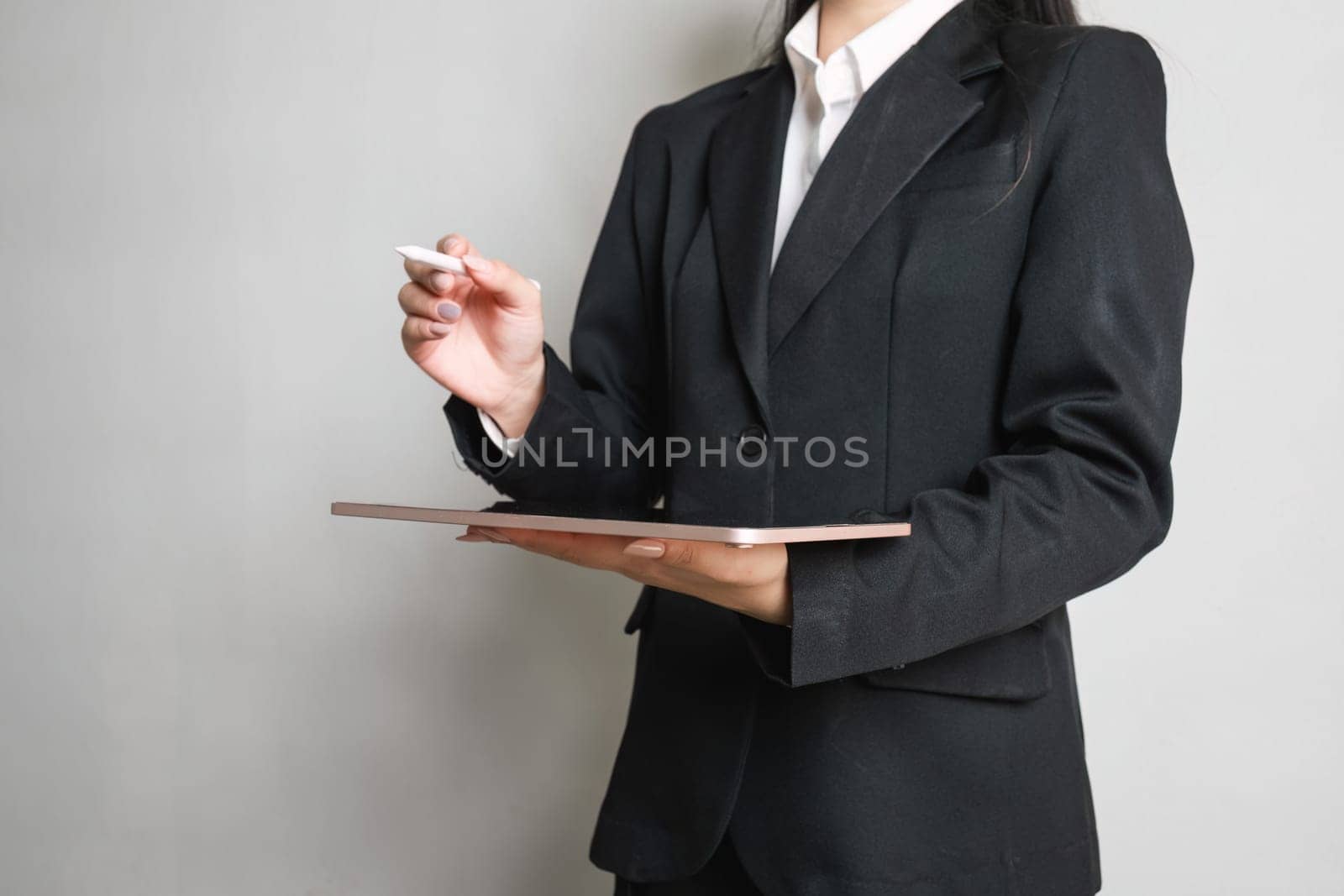 Close up smart Asian businesswoman holding her tablet and pointing tablet is pen up on empty space by wichayada