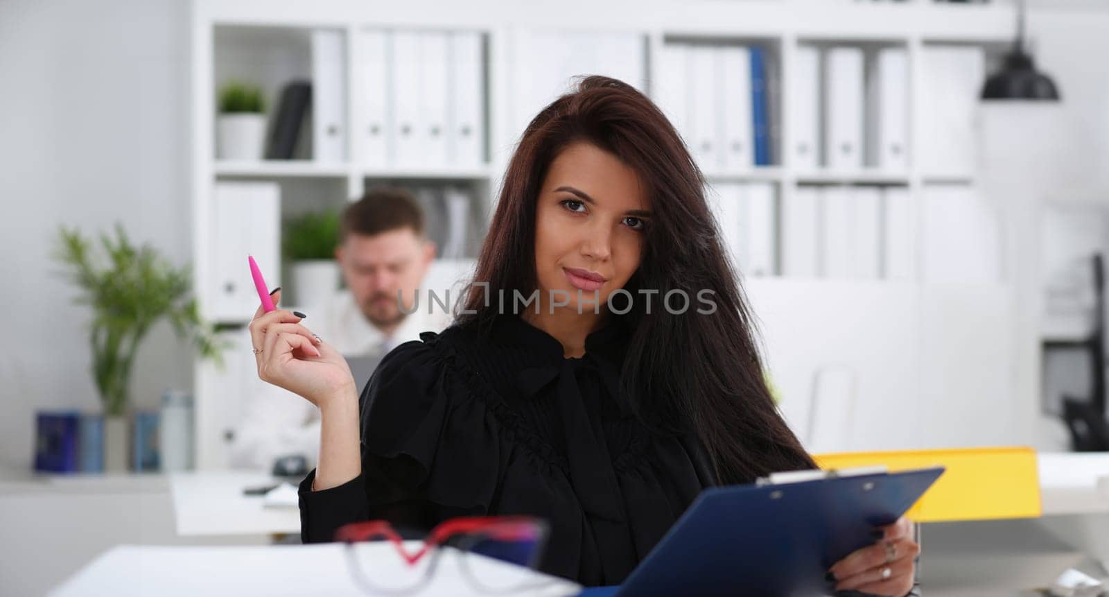 Beautiful smiling brunette woman hold in arms pink pen and paper clipped to pad portrait. White collar worker at workspace officer highly pay smart serious headhunter offer