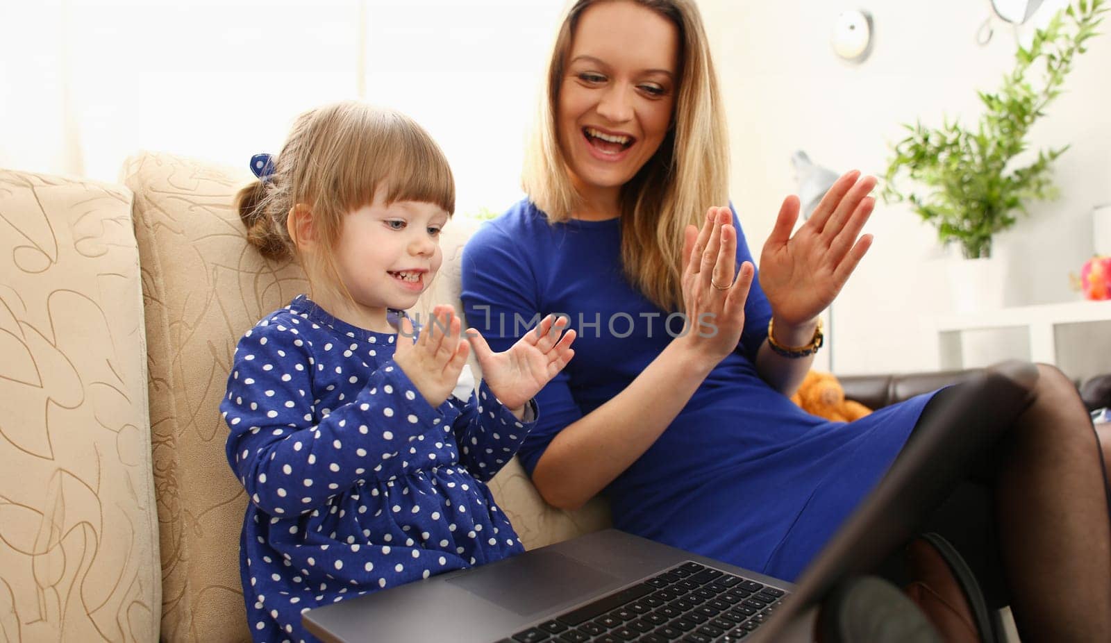 Cute little girl on couch with mom use laptop by kuprevich