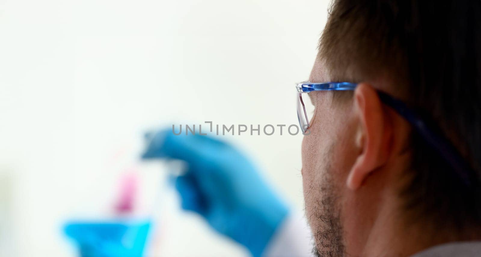 A male chemist holds test tube of glass by kuprevich