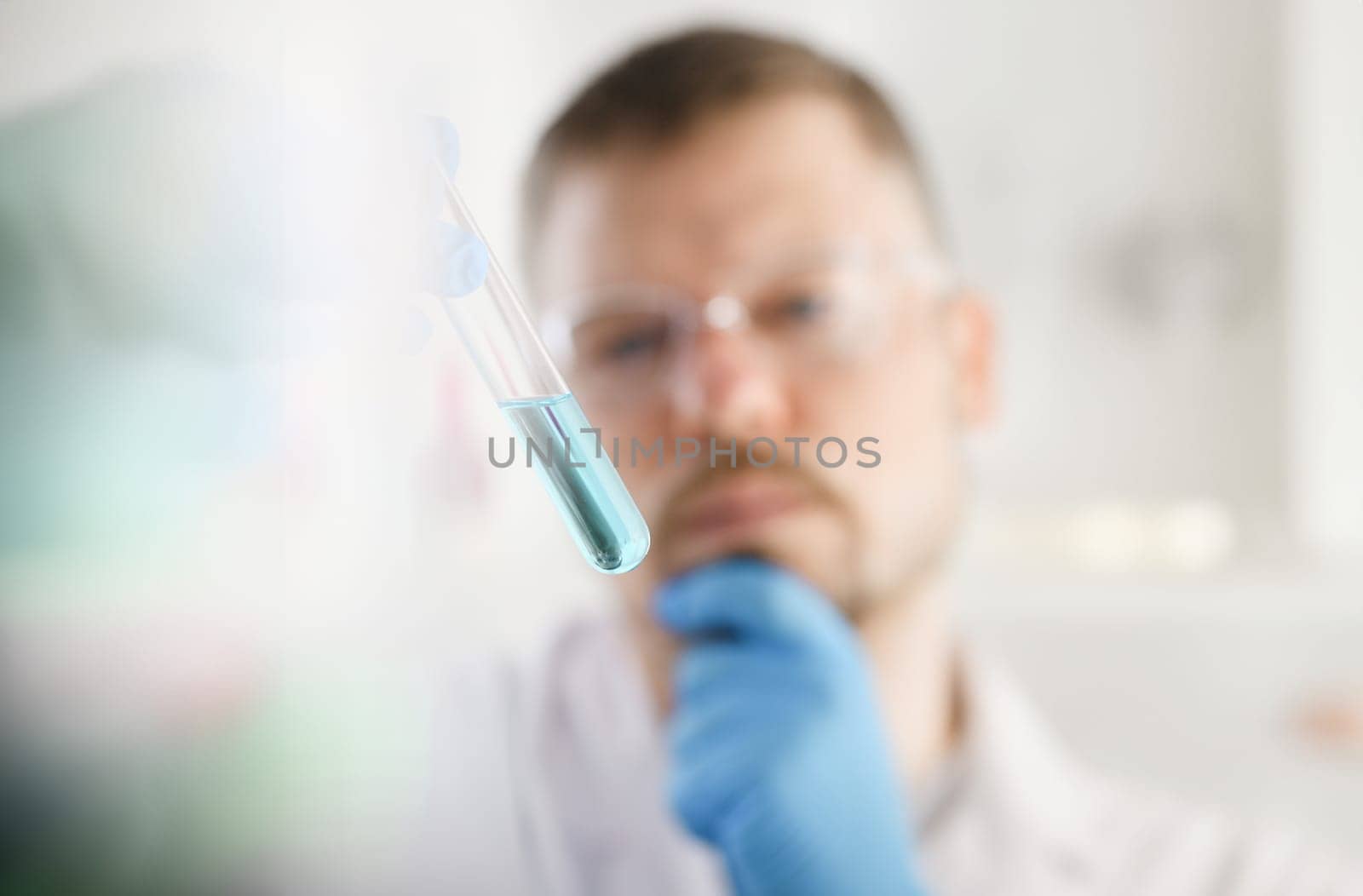 A male chemist holds test tube of glass by kuprevich