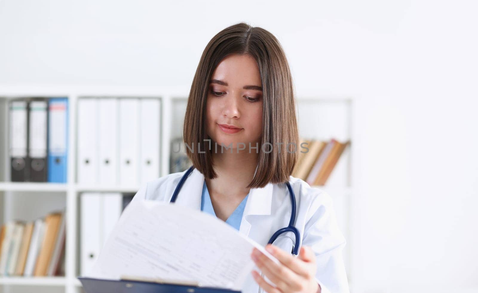 Female medicine doctor hand holding silver pen looking in clipboard pad closeup. Ward round patient visit check 911 medical calculation and statistics concept. Physician ready to examine patient