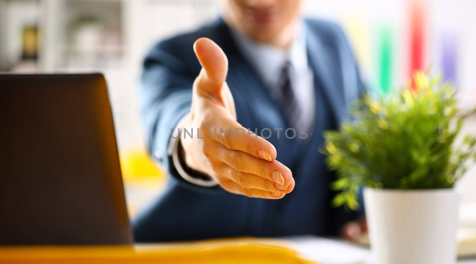 Man in suit and tie give hand as hello in office by kuprevich