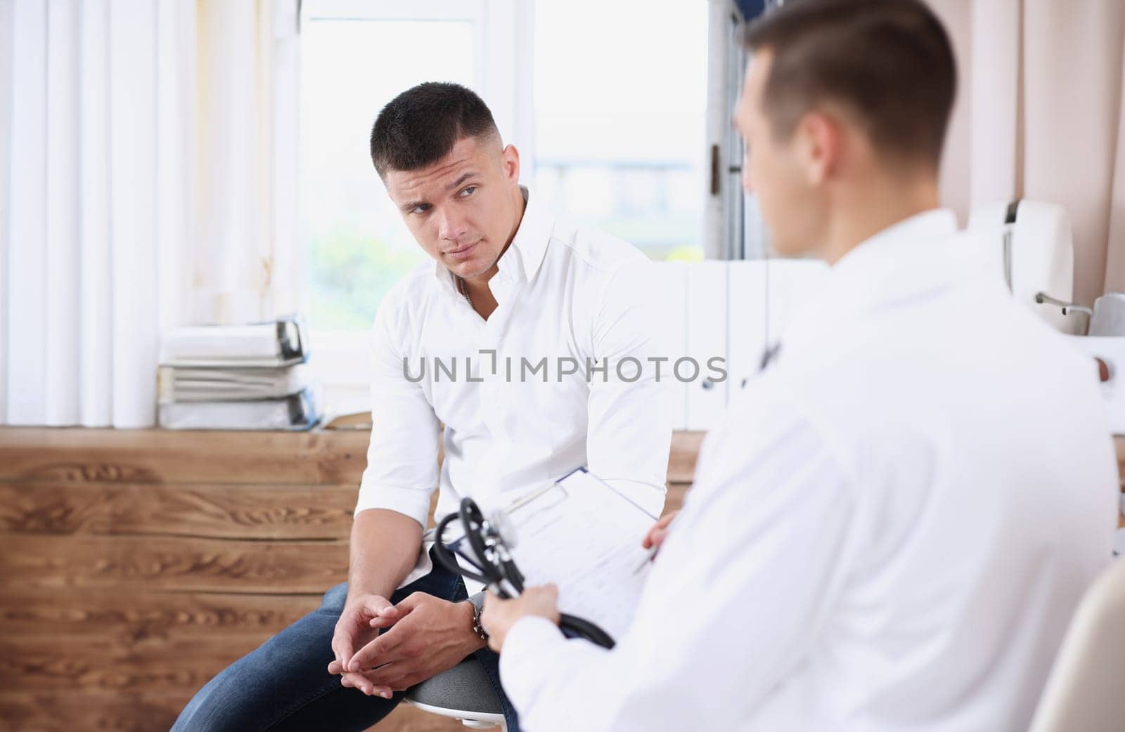 Male patient portrait with doctor filling patient history list at clipboard pad. Physical exam er trauma pain disease prevention ward round 911 prescribe remedy healthy lifestyle concept