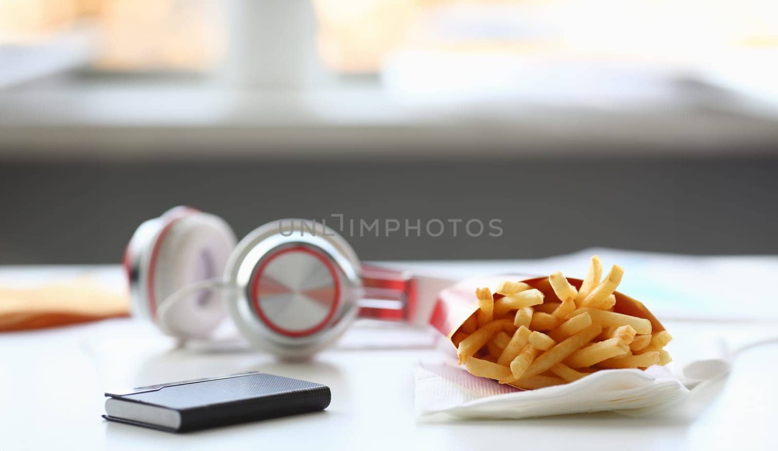 French fries with headphones lying on table in office during lunch break food delivery concept