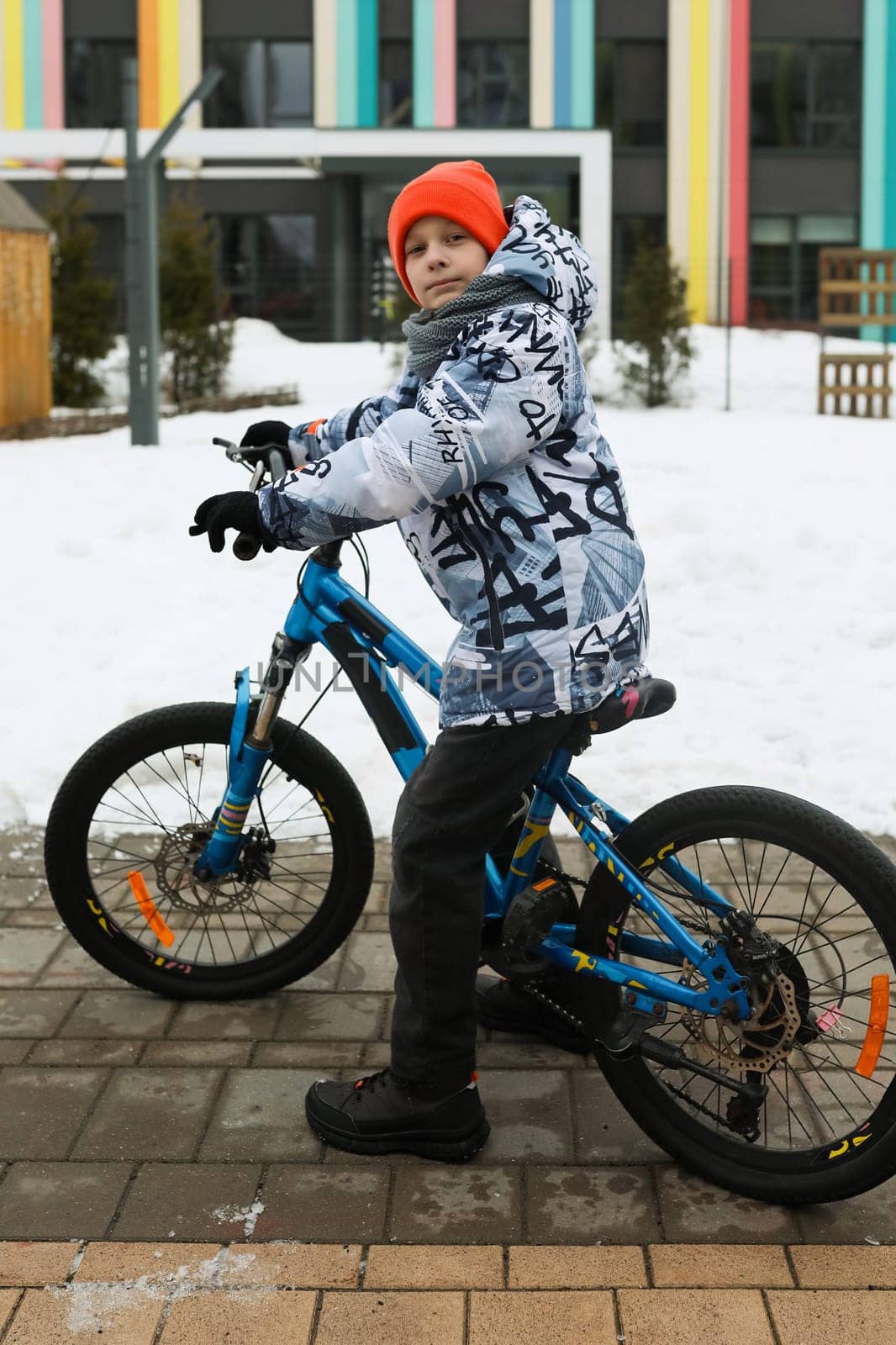 European child riding a bicycle in the yard in winter.