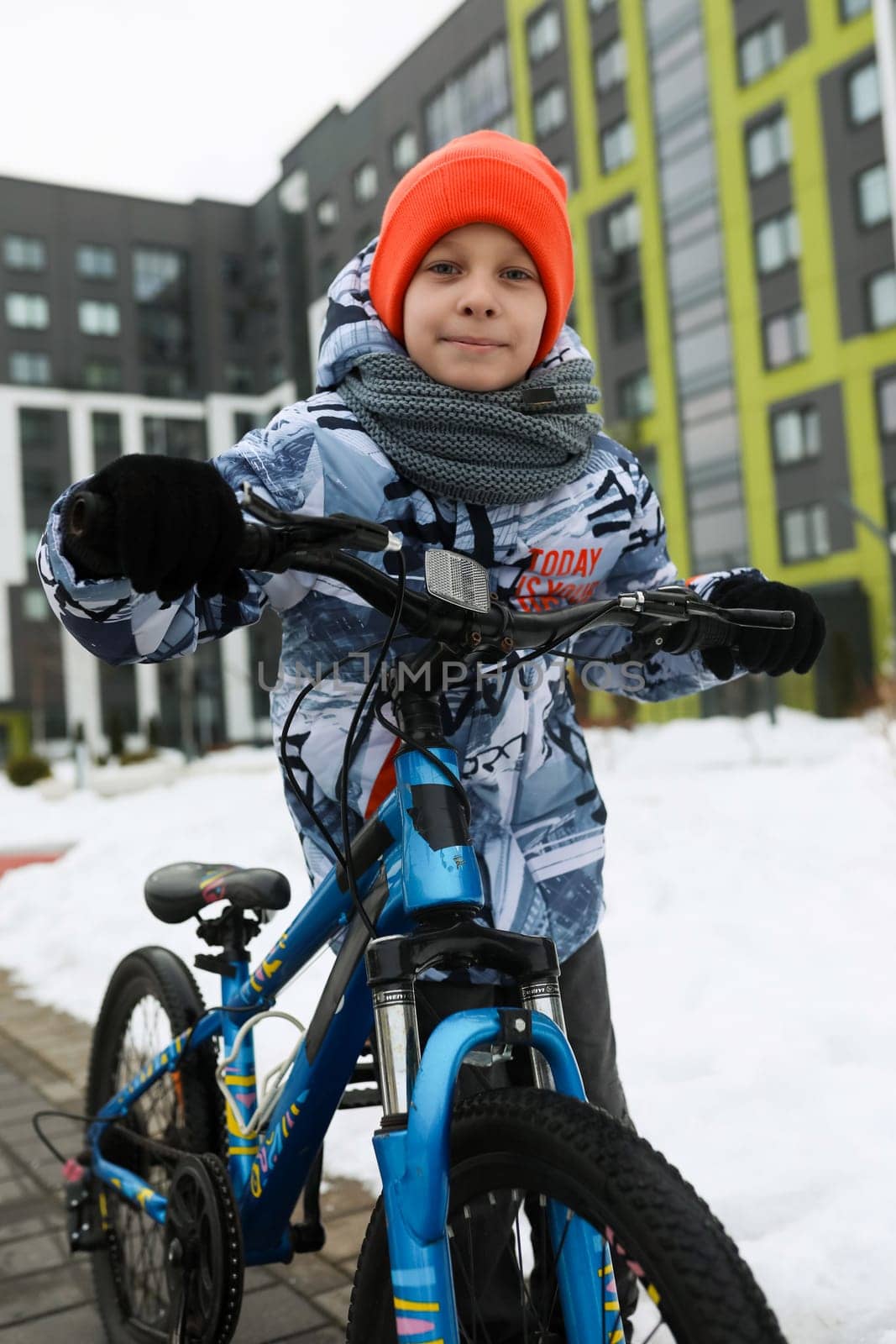 European child riding a bicycle in the yard in winter by TRMK