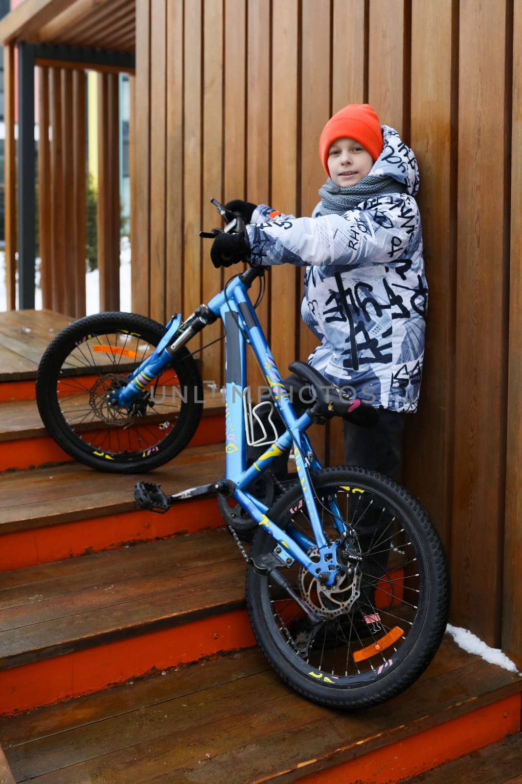 A boy in winter clothes rides a bicycle during the holidays.