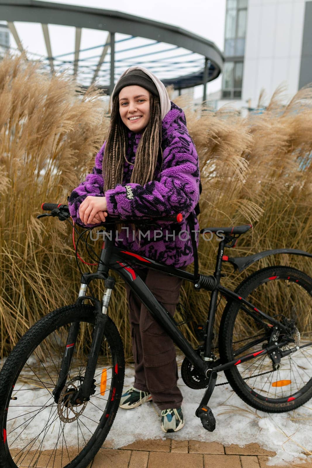 Bicycle rental concept. Young woman with dreadlocks rides a bicycle in the city.