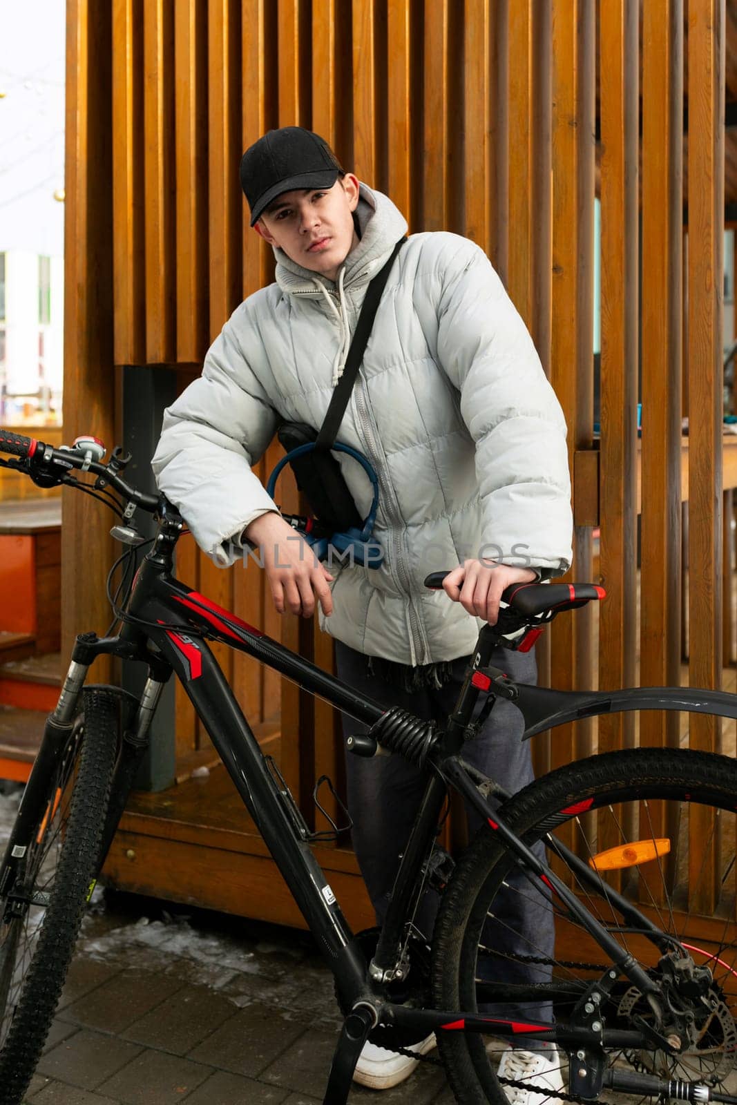 Bike rental concept. A man walks through the city in winter with a bicycle.
