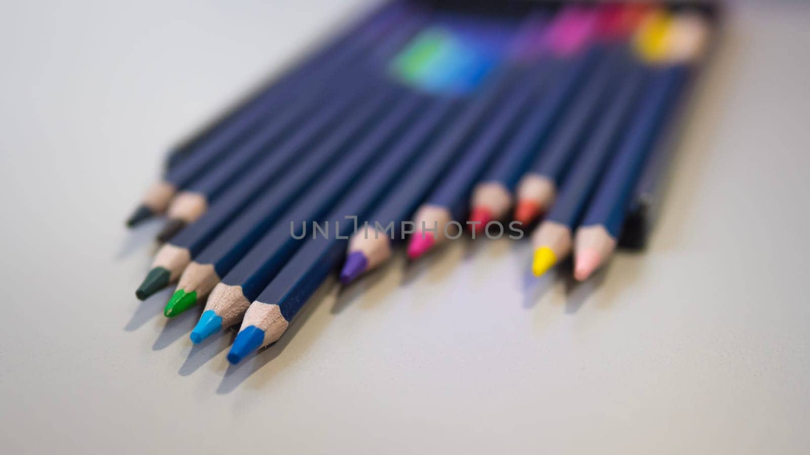 A variety of colored pencils are neatly arranged in a row on a table, resembling a colorful array of office supplies